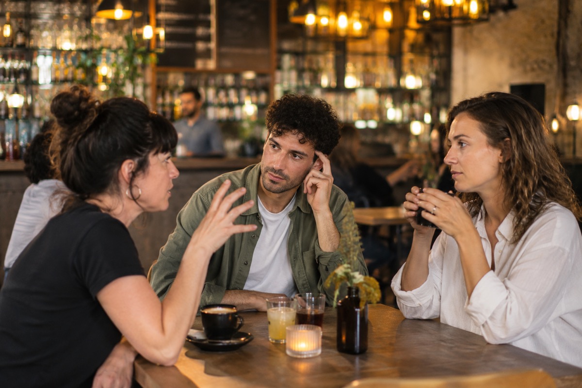Trois psychologues en discussion attentive autour d'une table de café.